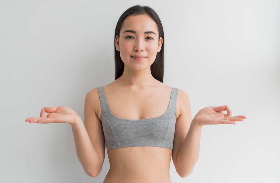 穿著灰色運動內衣的亞洲女性微笑伸展，象徵術後恢復狀態良好