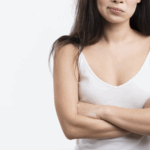 一位女性雙手輕輕按在畫有虛線標記的胸部上，背景模糊為藍色和白色