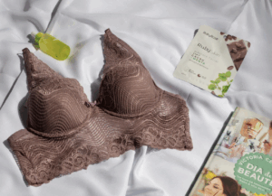 蕾絲內衣褲套裝與保養品擺拍/棕粉色蕾絲胸罩和內褲/白色床單上的美容雜誌、面膜和化妝水/女性內在美與日常保養