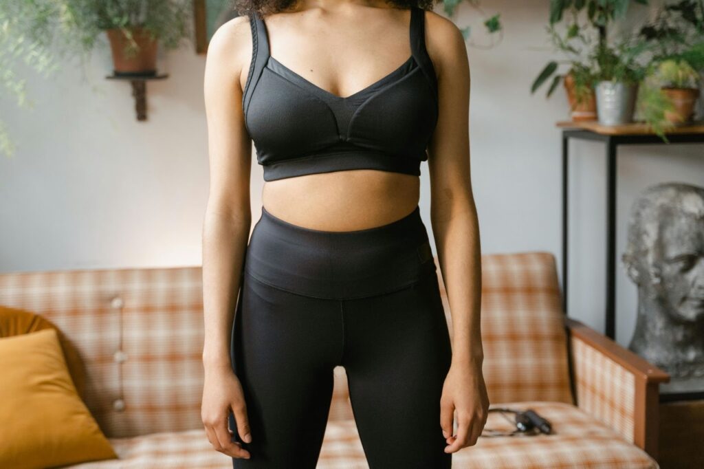 特寫一位女性身著白色寬鬆襯衫坐於沙發上，雙手自然交疊於膝上，畫面柔和明亮，展現輕鬆安心氛圍。