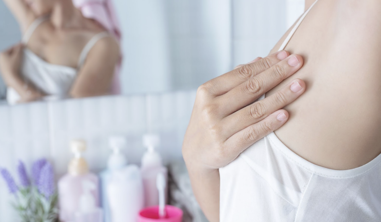 一名女性在浴室鏡子前，手部撫摸腋下肌膚的特寫畫面