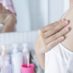 一名女性在浴室鏡子前，手部撫摸腋下肌膚的特寫畫面