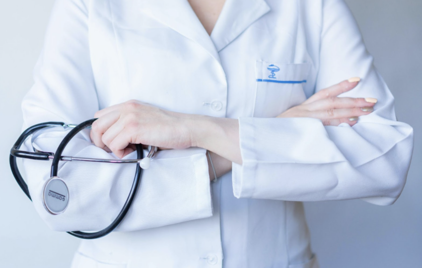 一名身穿白色護理人員服裝的人員，雙臂交叉並手持一副黑色聽診器