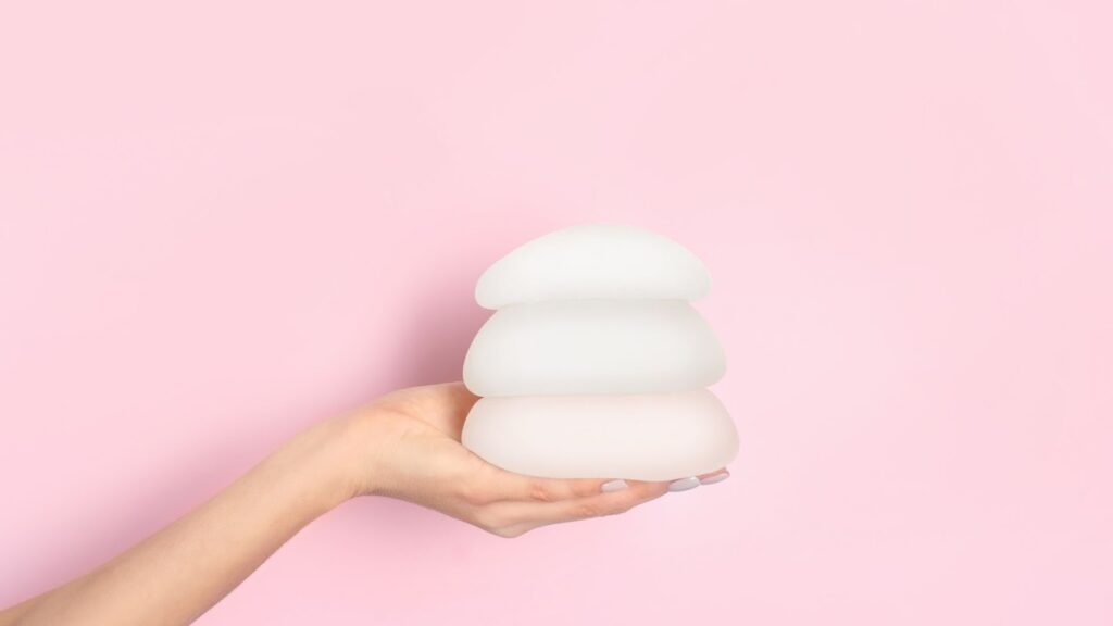 醫學美容診所工作人員手持三款不同尺寸與高度的圓盤型矽膠隆乳假體，展示產品的多樣選擇