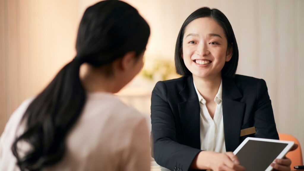 醫美診所諮詢師面帶微笑持平板電腦，與客戶進行一對一的隆乳手術方案溝通與需求分析