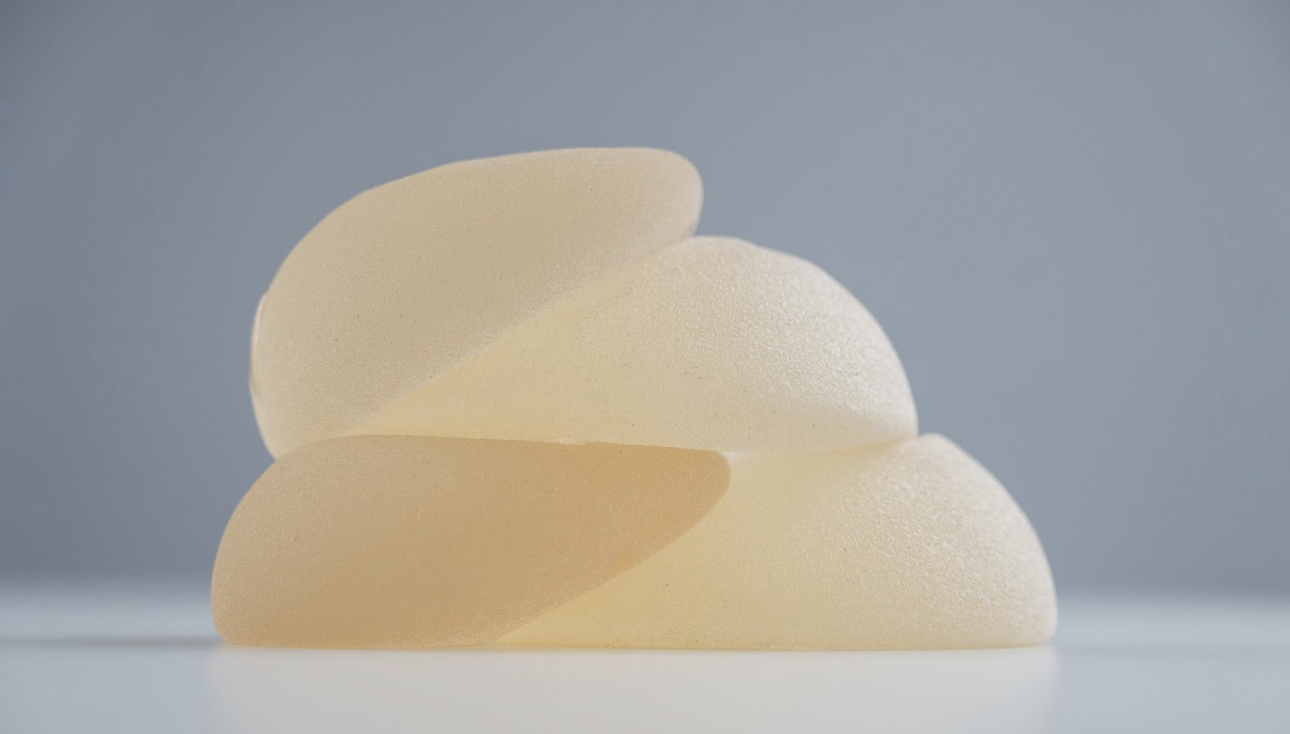 三個不同尺寸與形狀的霧面矽膠隆乳植體堆疊展示，呈現果凍矽膠的質地與自然水滴形弧度