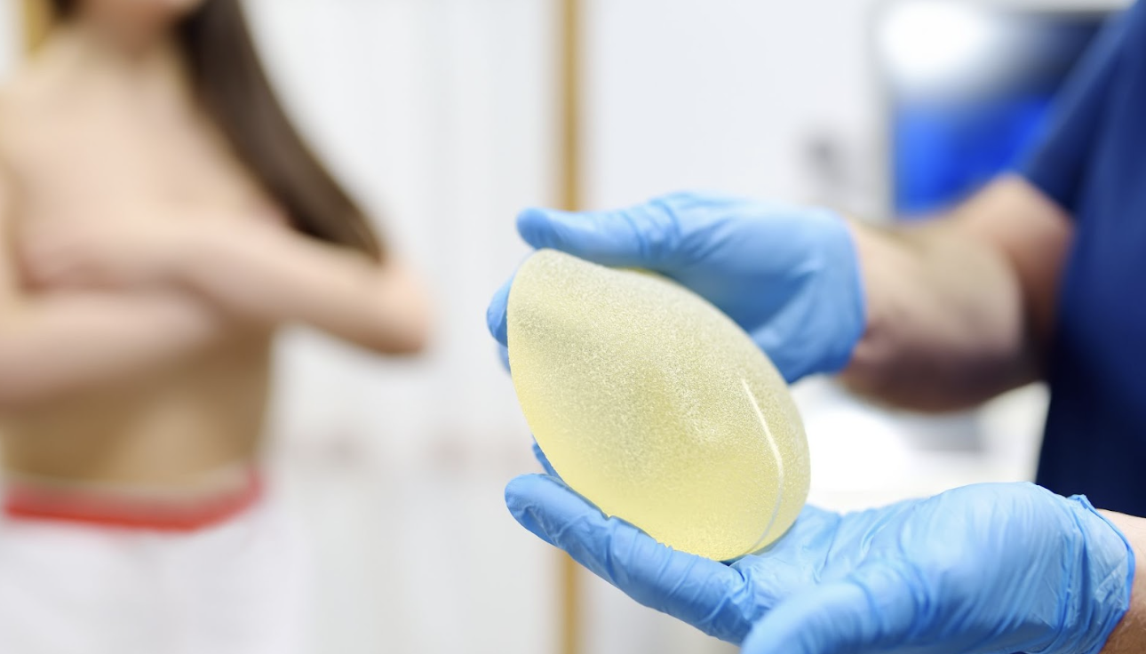 醫護人員雙手展示一個圓盤狀的毛面矽膠隆乳假體，清晰呈現植體的高凝聚力質地