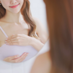 術後女性在鏡前檢查胸部形態展現自信微笑