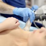 醫療人員使用超音波掃描儀對女性患者的胸部進行檢查，確保組織健康或監測植入物狀態，畫面呈現專業醫療診斷流程