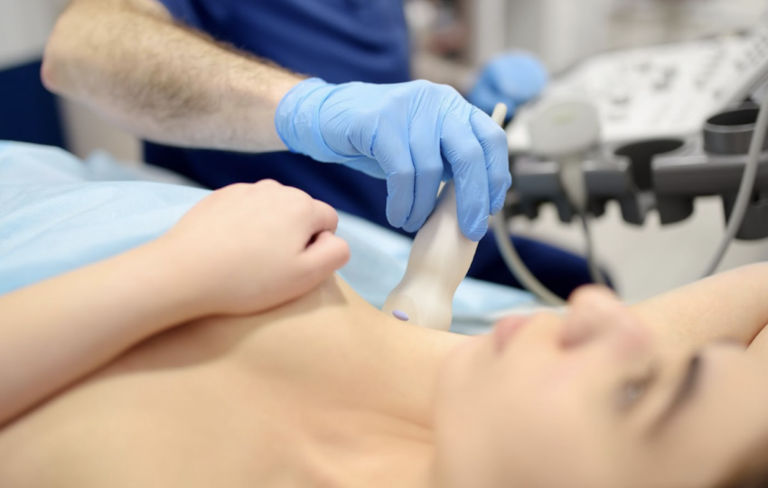 醫療人員使用超音波掃描儀對女性患者的胸部進行檢查，確保組織健康或監測植入物狀態，畫面呈現專業醫療診斷流程